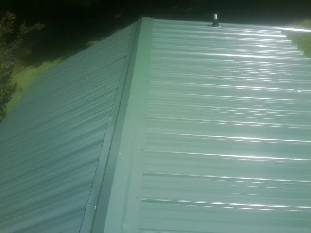 New green metal panels meeting at the ridge of a roof — Flat Roof Repair work by our crew in Clear Brook