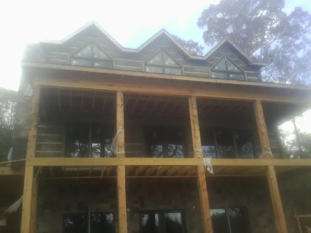 Dormers and porch framing on a large log home under construction — Roof Coating work by our crew in Clear Brook