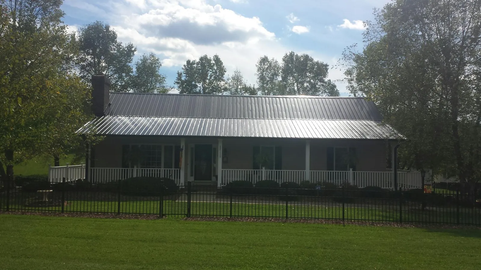 Gray metal roof on a brick ranch with a full width front porch — Gutter Guard Installation work by our crew in Clear Brook
