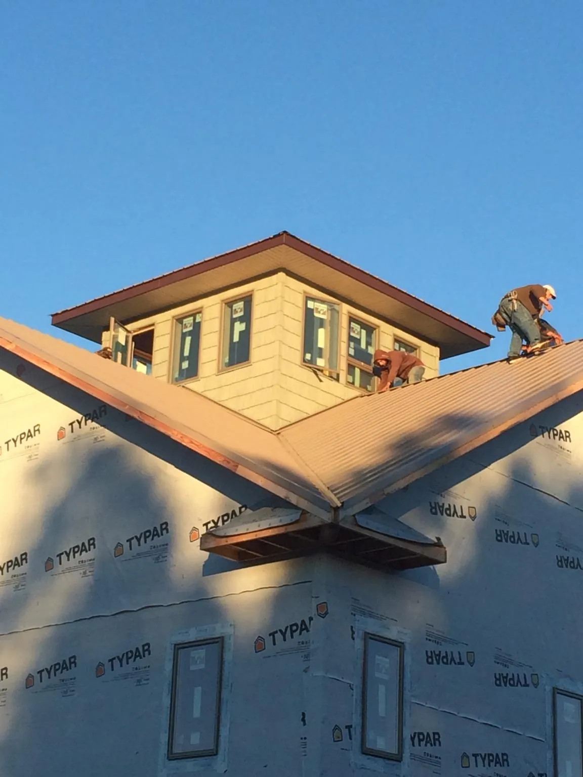 Roofers working around a rooftop cupola on a new metal roof at sunset — Roof Waterproofing in Clear Brook by Roofing Brothers